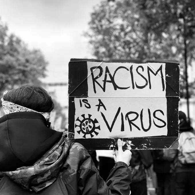 protester with sign that reads "Racism is a Virus"